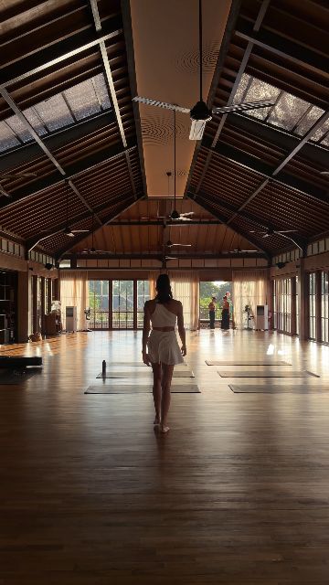A woman performs a yoga sequence in a sunlit studio.