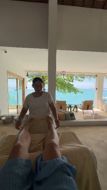 A person receives a massage at a tropical resort with an ocean view.